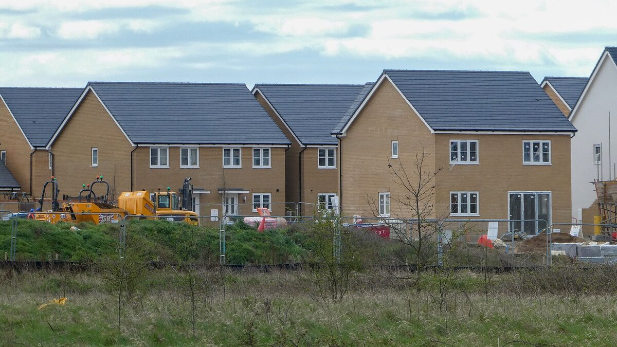 A row of newly built family homes on a fresh suburban development, new white-framed windows across every frontage